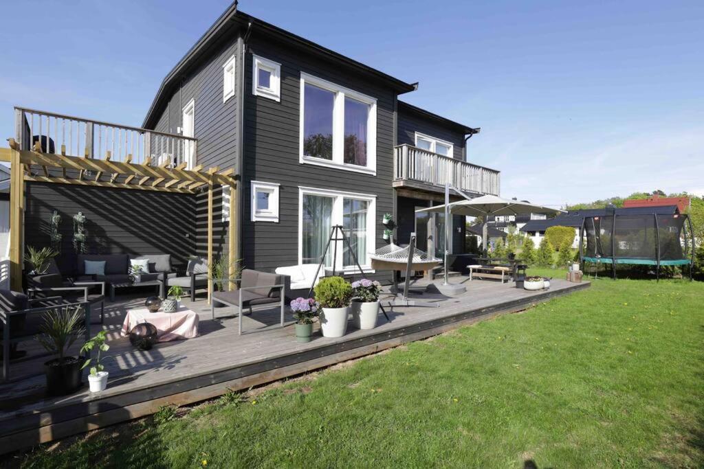 a black house with a deck with furniture on it at Sjønært hus på idylliske Husøy in Tønsberg