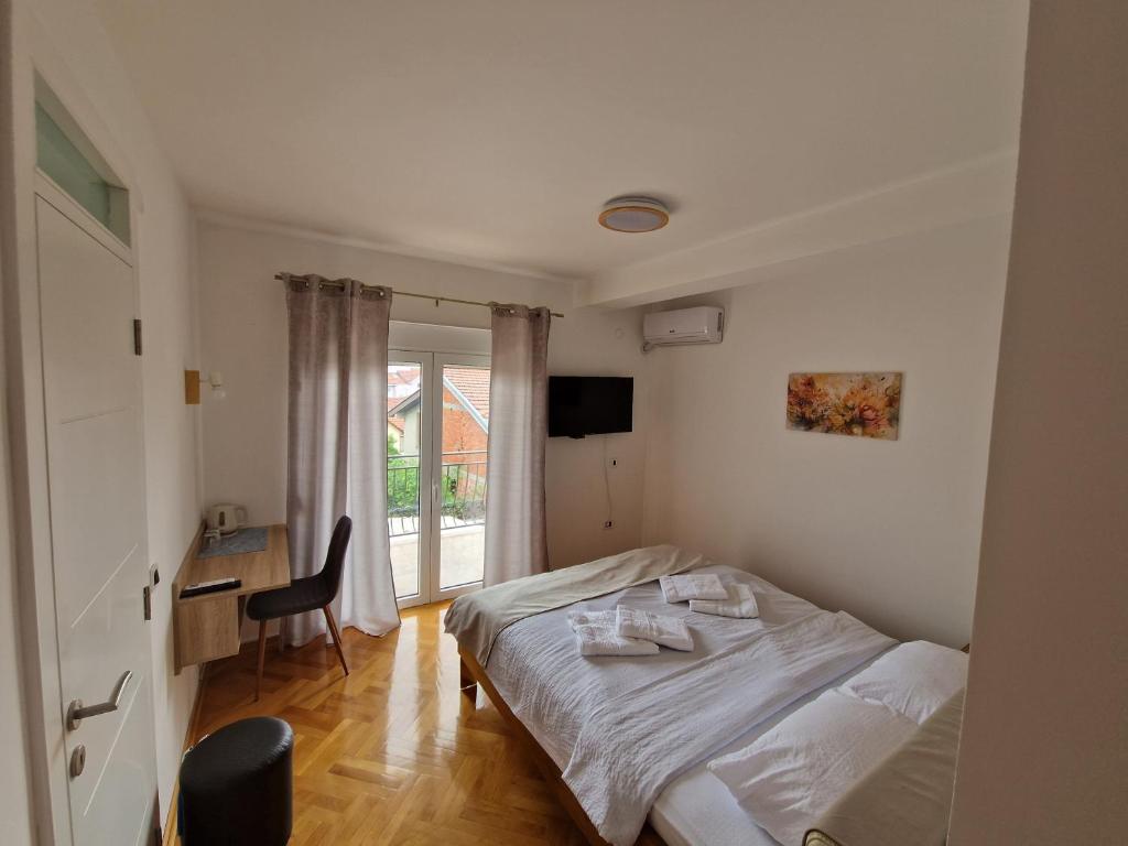 a bedroom with a bed and a desk and a window at Apartman Cvetkovic in Vranje