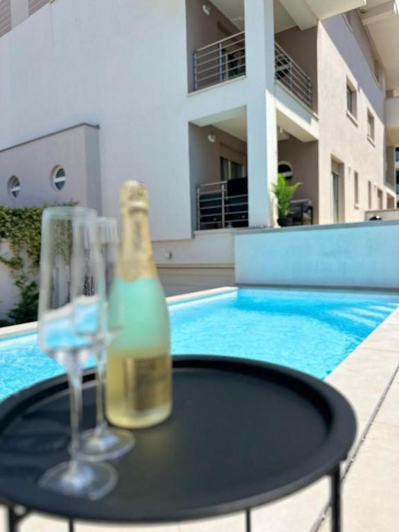 a bottle of wine and two glasses on a table near a swimming pool at Volme Resort in Banjole