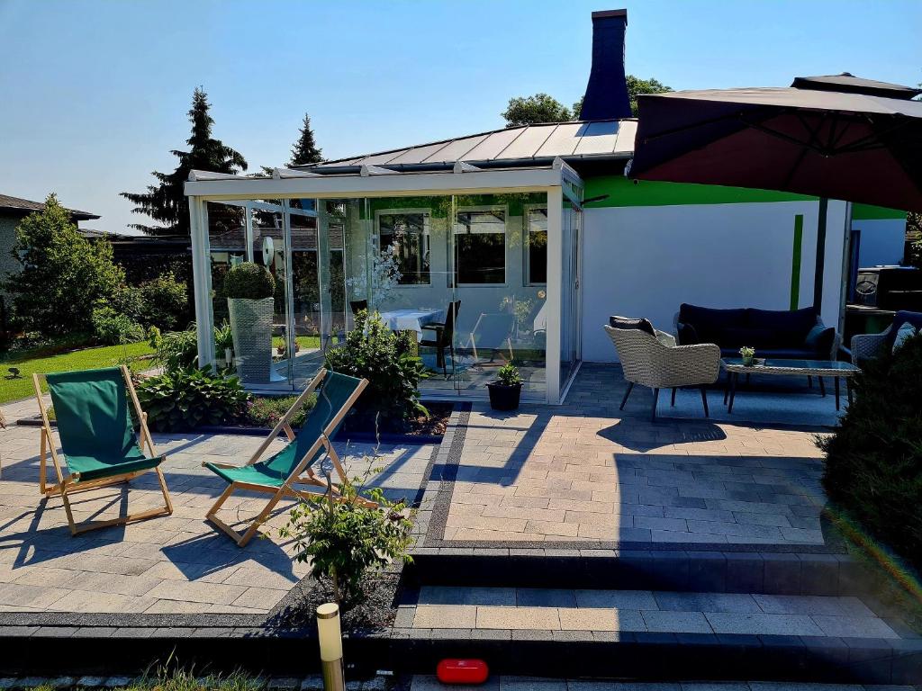 eine Terrasse mit 2 Liegestühlen und einem Sonnenschirm in der Unterkunft Ferienhaus Grüner Bungalow in Stendell