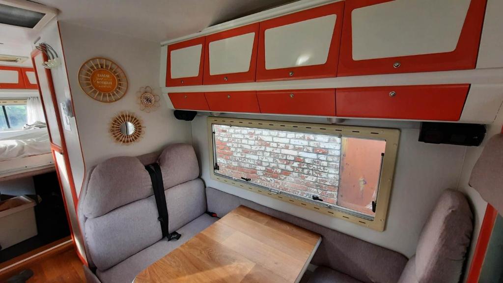 an interior of a rv with a window and a table at Camping car à 3 minutes du parc Pairi Daiza in Brugelette