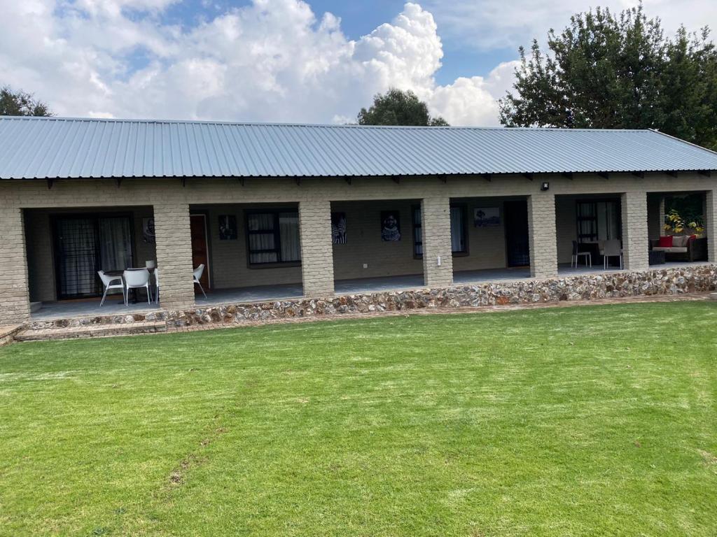 a house with a grass field in front of it at Zacks Country Stay Self-catering in Krugersdorp