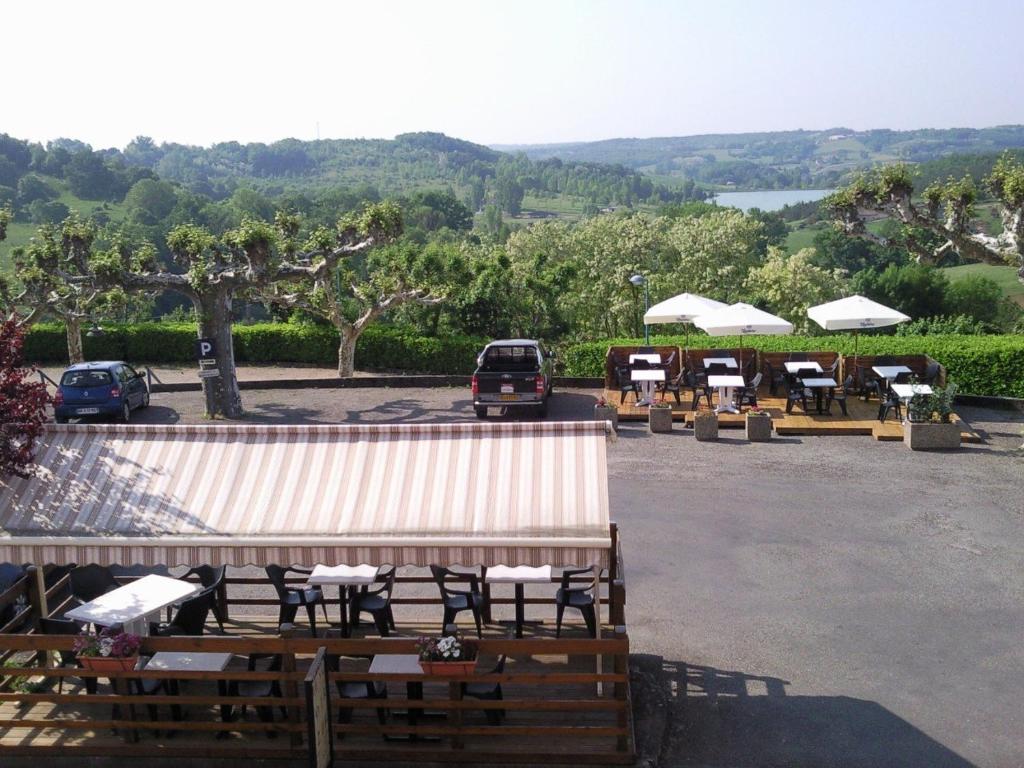 um grupo de mesas e guarda-sóis num parque de estacionamento em Logis L'Auberge du Quercy Blanc em Molières