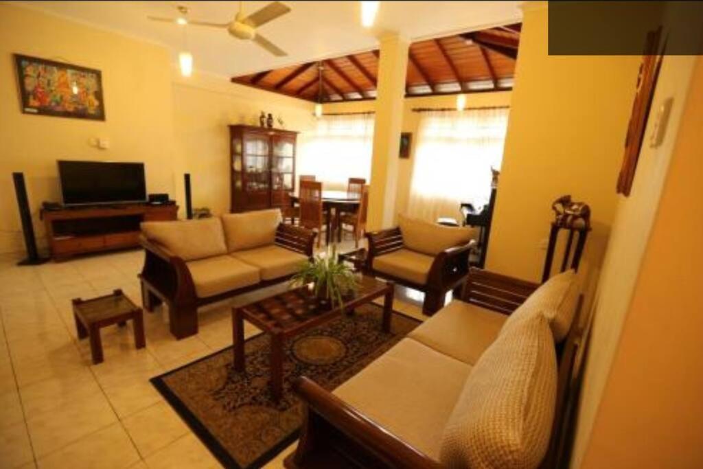 a living room with a couch and chairs and a television at Reverie Hill Bungalow, Kandy in Kandy