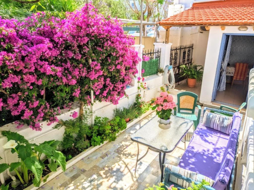 a patio with pink flowers and a table and chairs at House with garden in city of Rhodes in Rhodes Town