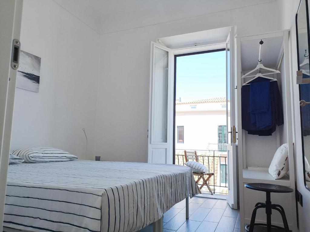 una camera bianca con letto e balcone di DomoMea - L'Isola nell'Isola a La Maddalena