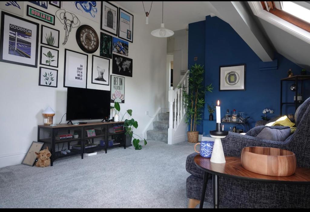 a living room with a tv and a blue wall at Penthouse suite, Victoria Apartments in Prestatyn