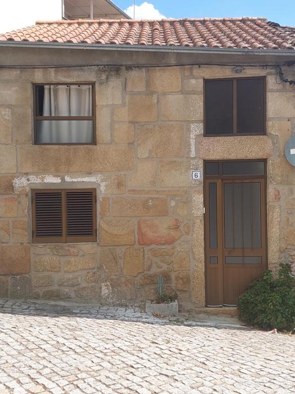 a stone house with a brown door and two windows at Casa da vila de Caria in Caria