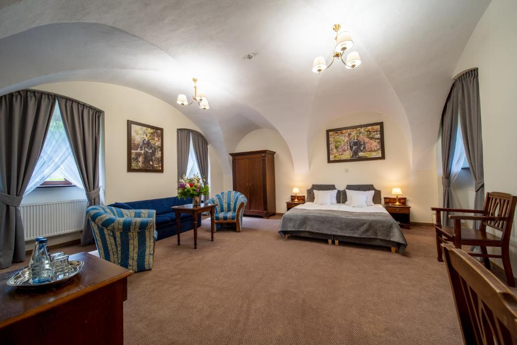 Large bedroom with vaulted ceiling, double bed, and seating area with armchairs.