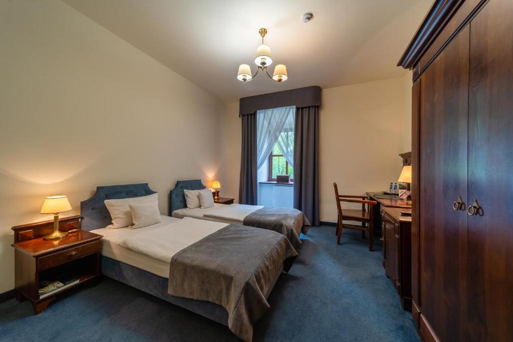 Cozy bedroom with twin beds, wooden furniture, and a window with curtains.