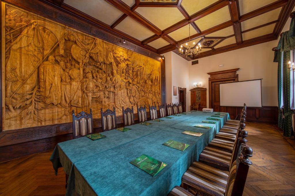 Long conference table with green tablecloth, surrounded by ornate wooden chairs.