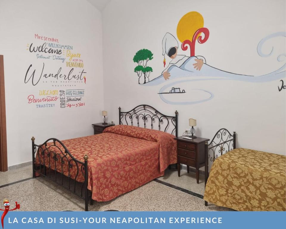 ナポリにあるLa casa di Susiのベッドルーム1室(ベッド2台付)が備わります。壁に壁画が飾られています。