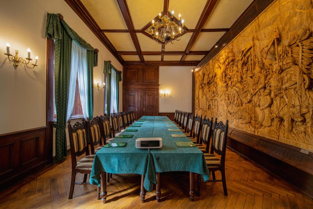 Conference room with green tablecloth, wooden chairs, and large wall tapestry.