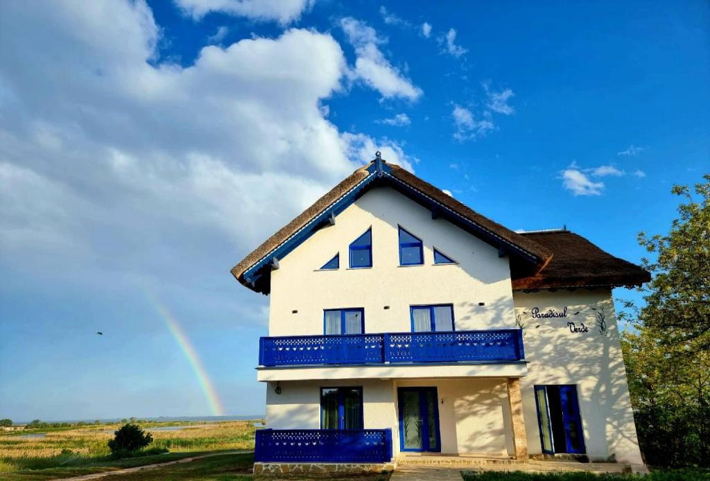 uma casa com um arco-íris ao fundo em Paradisul Verde em Jurilovca