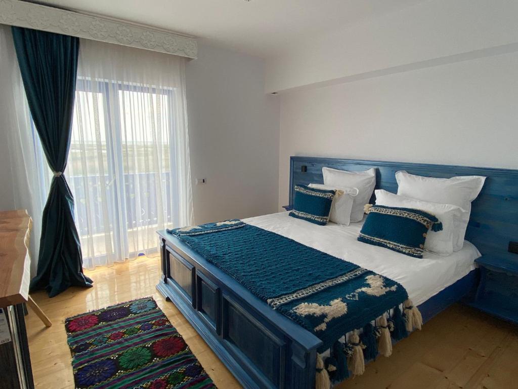 a blue bed in a room with a large window at Agropensiunea Paradisul Verde in Jurilovca