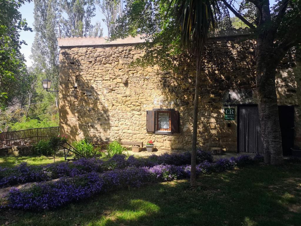 a stone house with a window and purple flowers at Casa rural Ardetxal a 16km de Logroño y Laguardia in Viñaspre