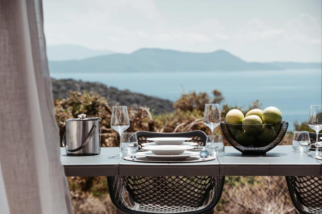 una mesa con un bol de frutas y copas de vino en Mesogi Villas, brand new modern, stylish villas, private pool, seaviews, en Meganisi