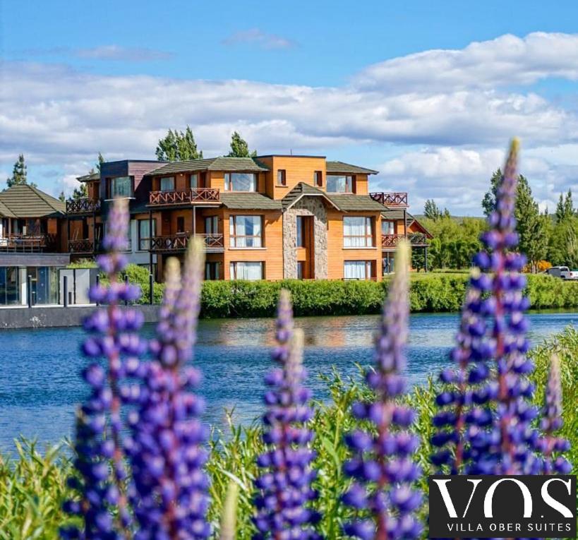a large house with purple flowers in front of it at Villa Ober Suites in Dina Huapi