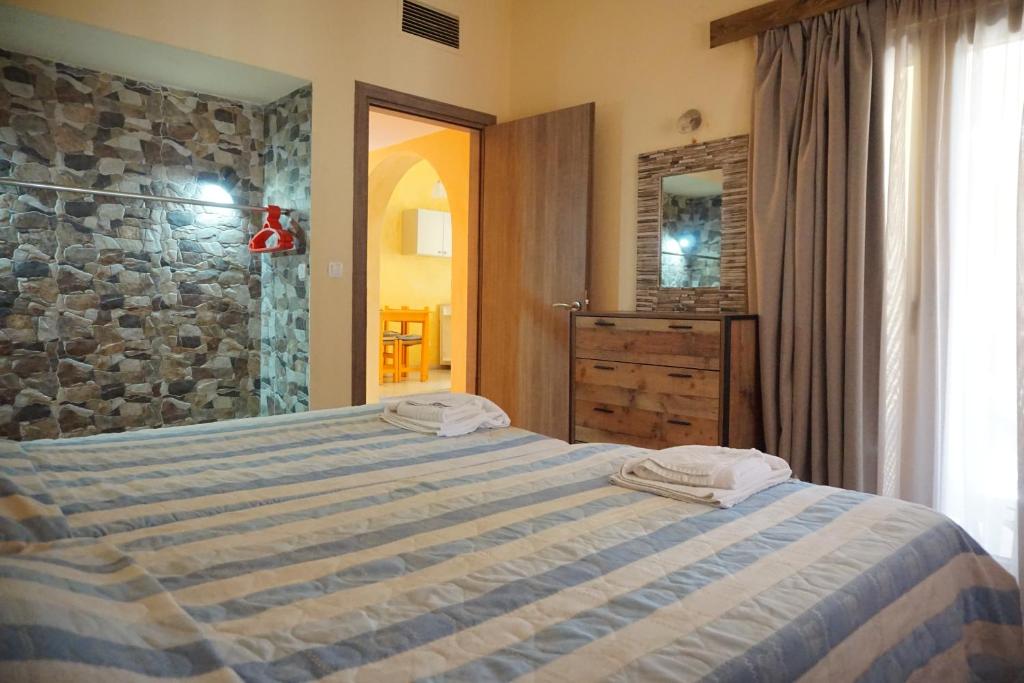 sypialnia z łóżkiem i kamienną ścianą w obiekcie Katerini Apartments Hotel w mieście Platanes