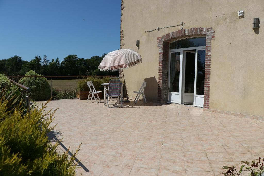 un patio con sillas y una sombrilla junto a un edificio en Gite les Gouleries chez Dominique, en Dangy