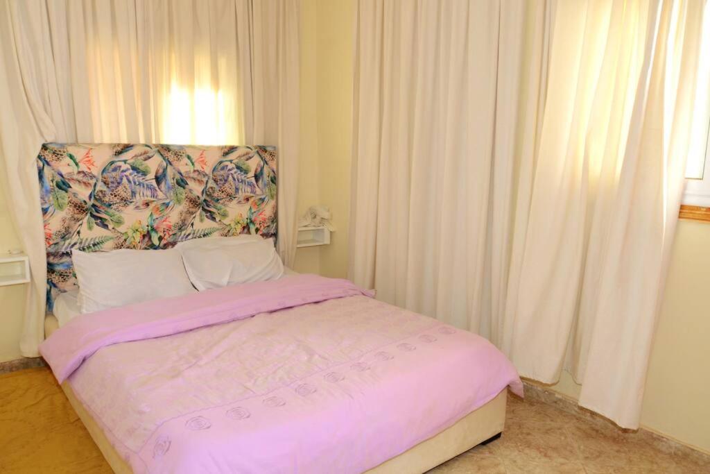 een slaapkamer met een roze bed met een hoofdeinde bij Cozy Home in Tamraght, Surfing, jet skiing, buggy. in Tamraght Ouzdar