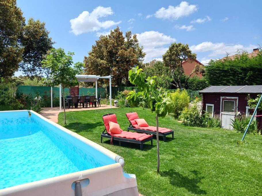 a backyard with a pool with chairs and a table at Chalet Las Dalias in El Espinar