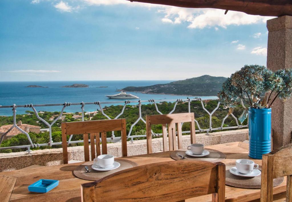 - une table en bois avec des chaises et une vue sur l'océan dans l'établissement Vistamare Grande Pevero, à Porto Cervo