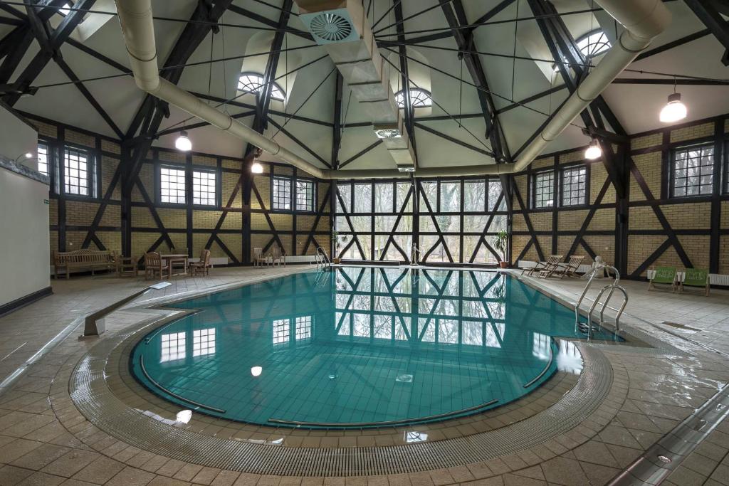 Circular indoor pool surrounded by wooden beams and seating.
