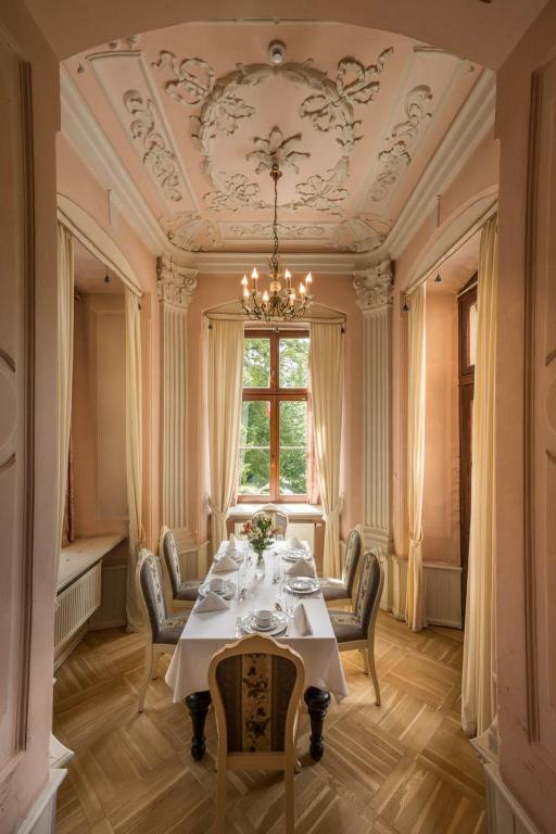 Elegant dining room with ornate ceiling, chandelier, and table set for tea.