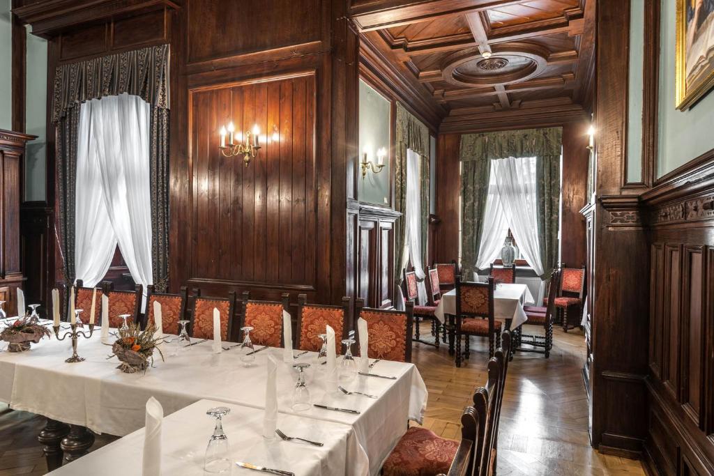 Dining room with white tablecloths, wooden paneling, and elegant chandeliers.