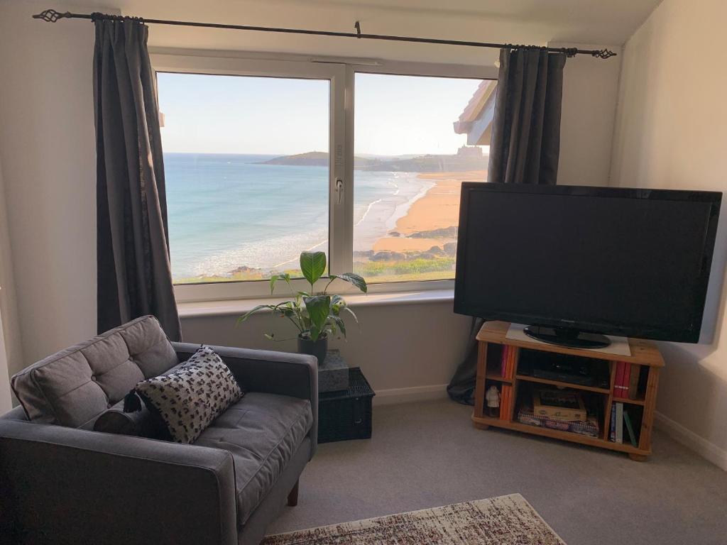 a living room with a tv and a large window at Two bed flat with stunning views over Fistral Bay! in Newquay