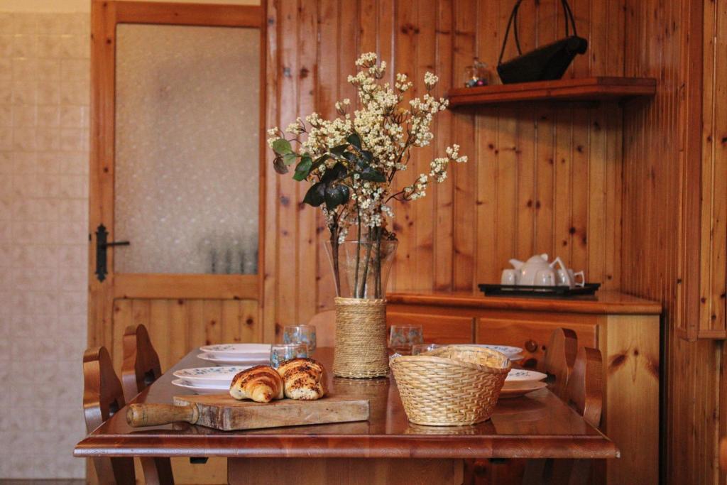 uma mesa com um vaso de flores e pão sobre ela em Wildwood Cottage em Serramazzoni