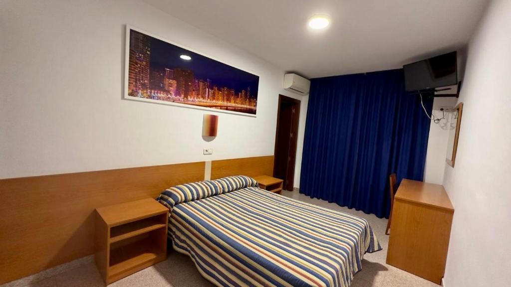 a hotel room with a bed and a tv at Pension La Orozca in Benidorm