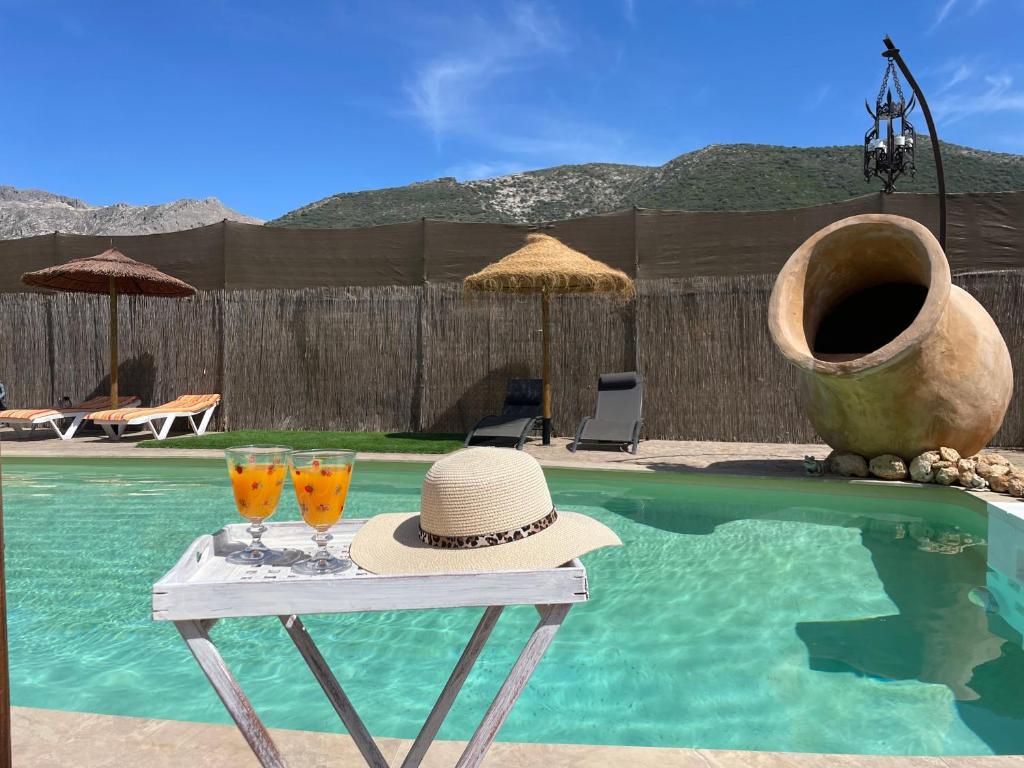 un sombrero y dos vasos en una mesa junto a una piscina en Casa La Tinaja, en Las Lagunillas