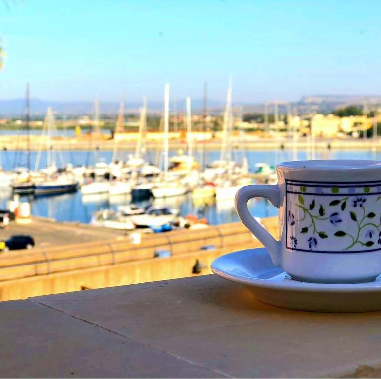 シラクーサにあるB&B Marina di Ortigiaのマリーナ付きのテーブルに座ったコーヒーカップ