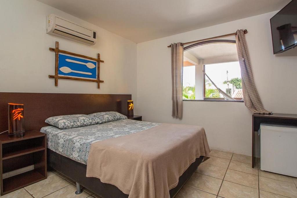1 dormitorio con cama y ventana en Suítes cambucá, en Paraty