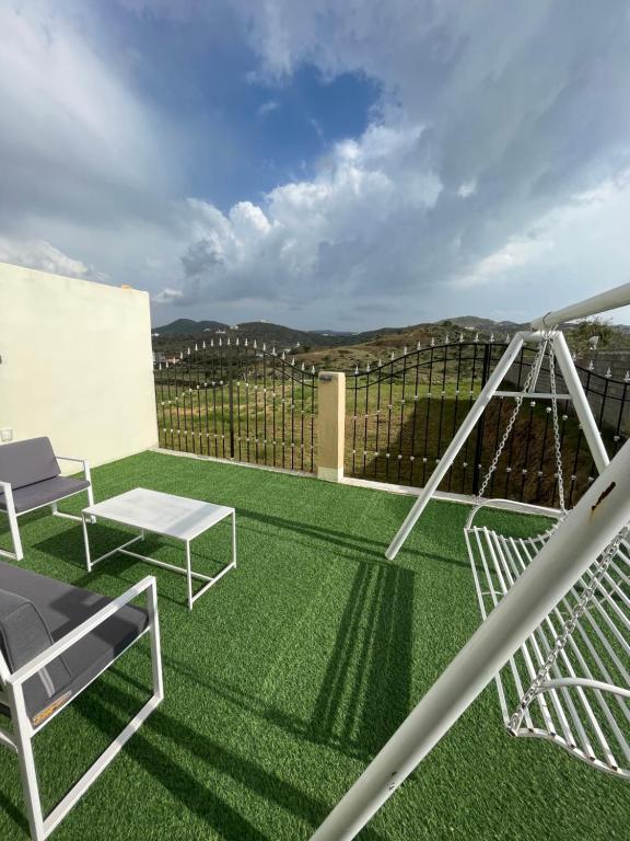 d'un balcon avec de l'herbe verte, une table et des chaises. dans l'établissement سحاب تهلل السودة Sahab AL-Sodah, à Sawdāʼ