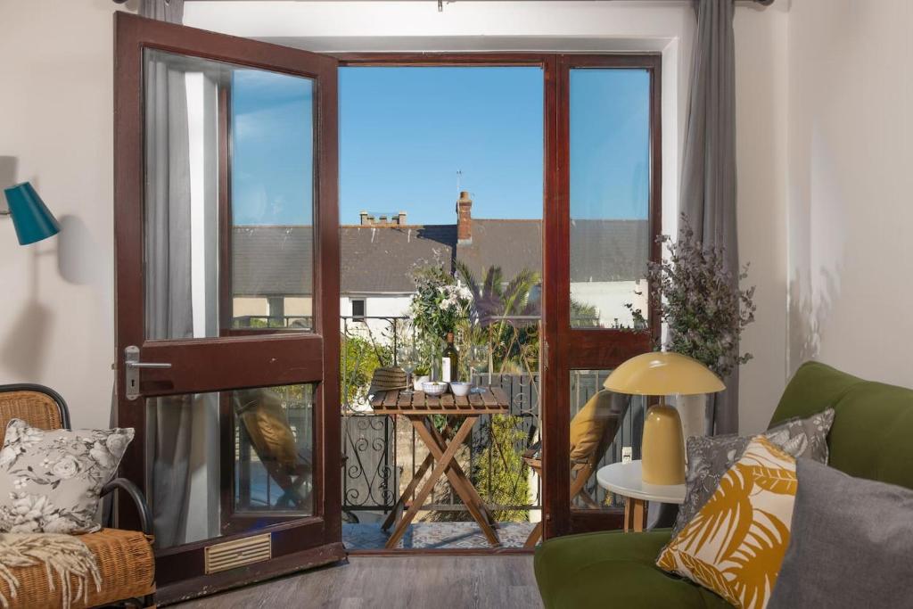 uma sala de estar com um sofá verde e uma porta de vidro deslizante em Quiet family-friendly apartment 250 metres from beach and town em Newquay