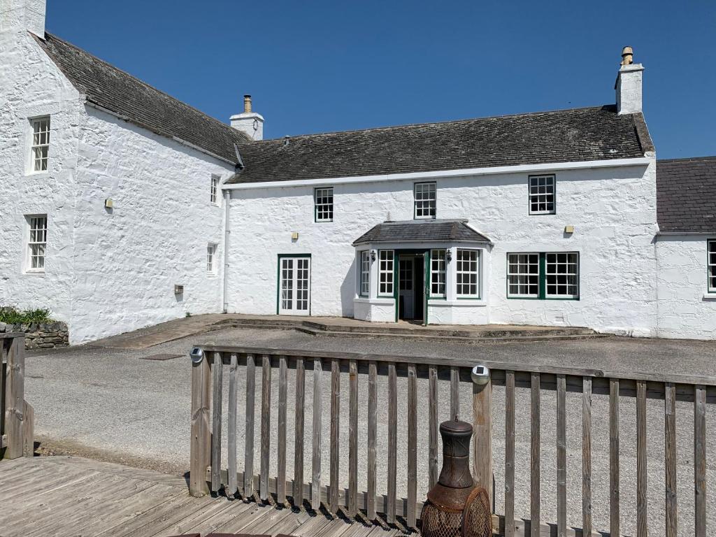 een wit bakstenen huis met een houten hek ervoor bij The Delnashaugh in Ballindalloch