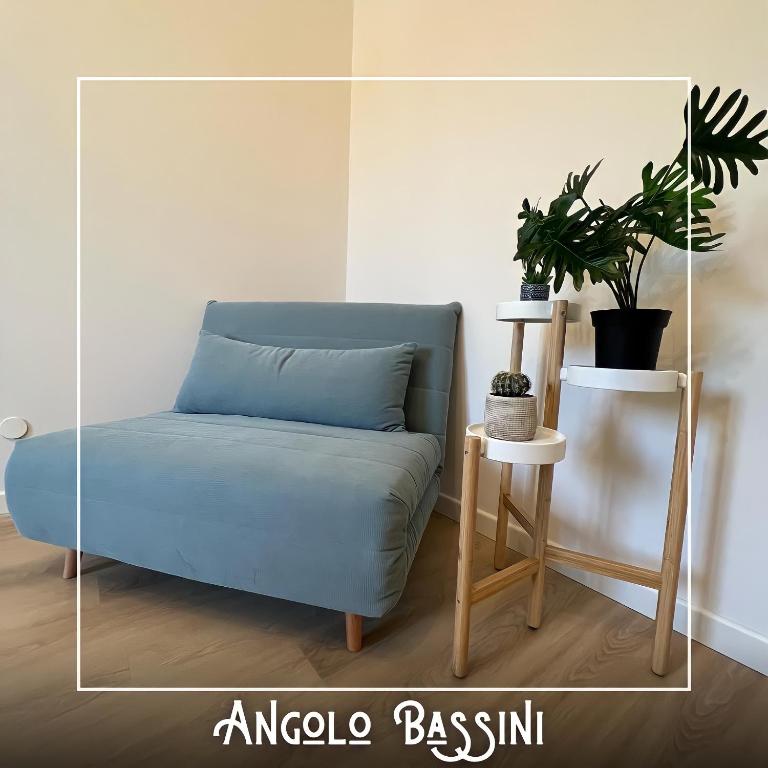 eine blaue Couch in einem Zimmer mit Pflanze in der Unterkunft Angolo Bassini - Apartment in Verona