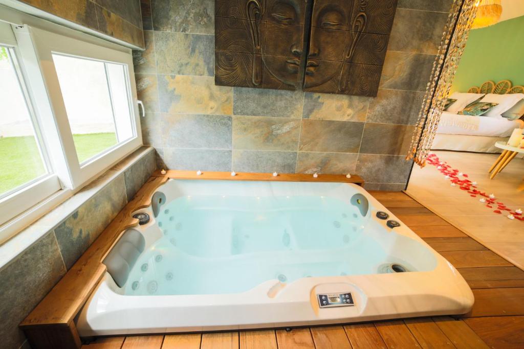 a large bath tub in a room with two windows at Ô Balinais mini villa avec spa et piscine privatif in Marseille