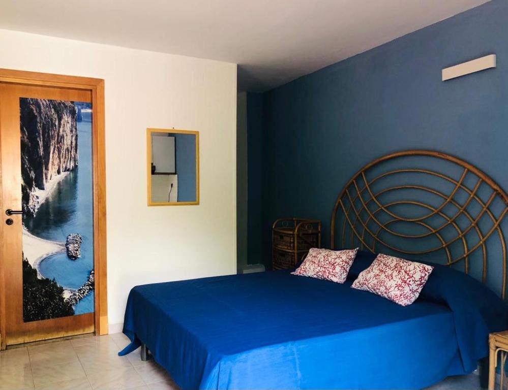 ein blaues Schlafzimmer mit einem Bett und einer blauen Wand in der Unterkunft Villaggio Residence Chalet degli Ulivi in Marina di Camerota
