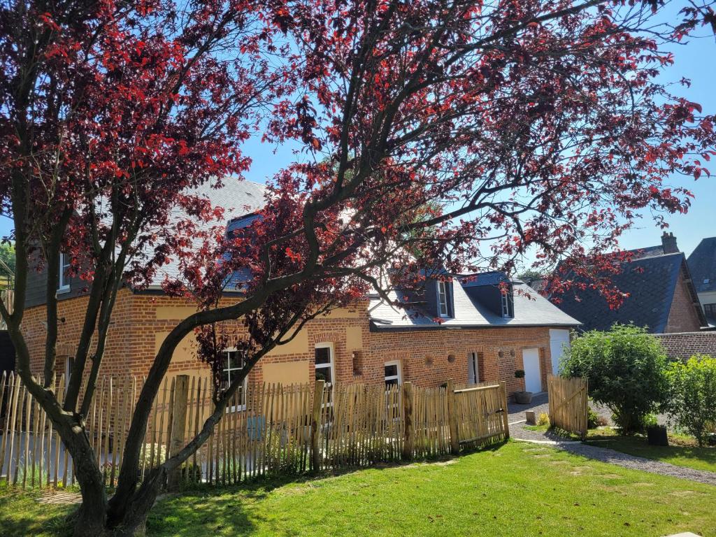 una casa con una valla y un árbol con hojas rojas en Les Fabulettes, en Auffay