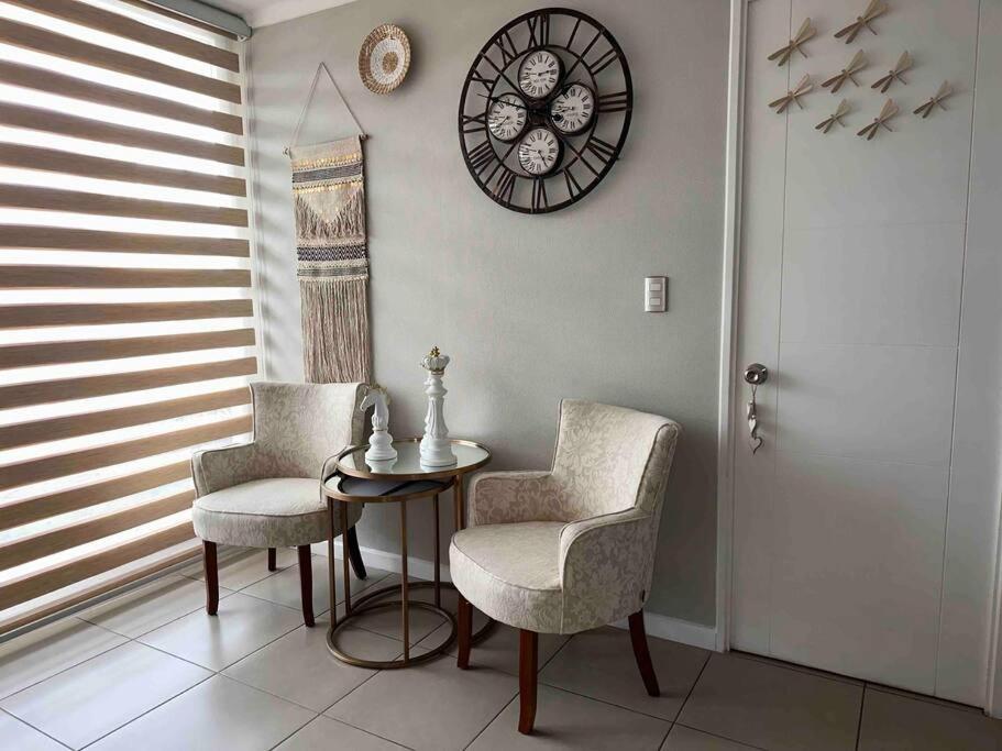 Habitación con 2 sillas, mesa y reloj en Descanso y Relajo Deluxe en La Serena, en La Serena