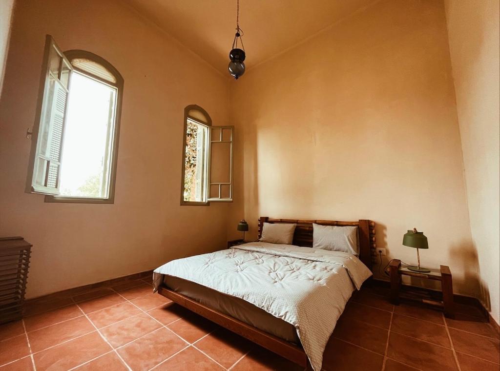 a bedroom with a bed and two windows at Domaine El Htouba in Korba
