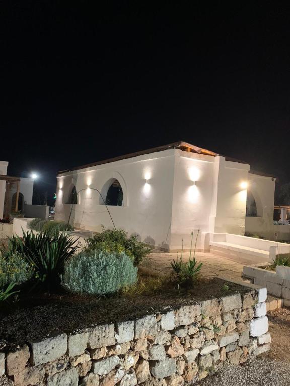 a white house at night with a stone wall at Masseria Piccole Taverne in Rosa Marina