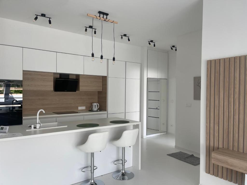a kitchen with white cabinets and a sink and stools at Christy’s House in Debrecen