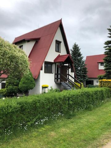 uma pequena casa branca com um telhado vermelho em Dom na Kaszubach Sulęczyno z widokiem na jezioro em Suleczyno