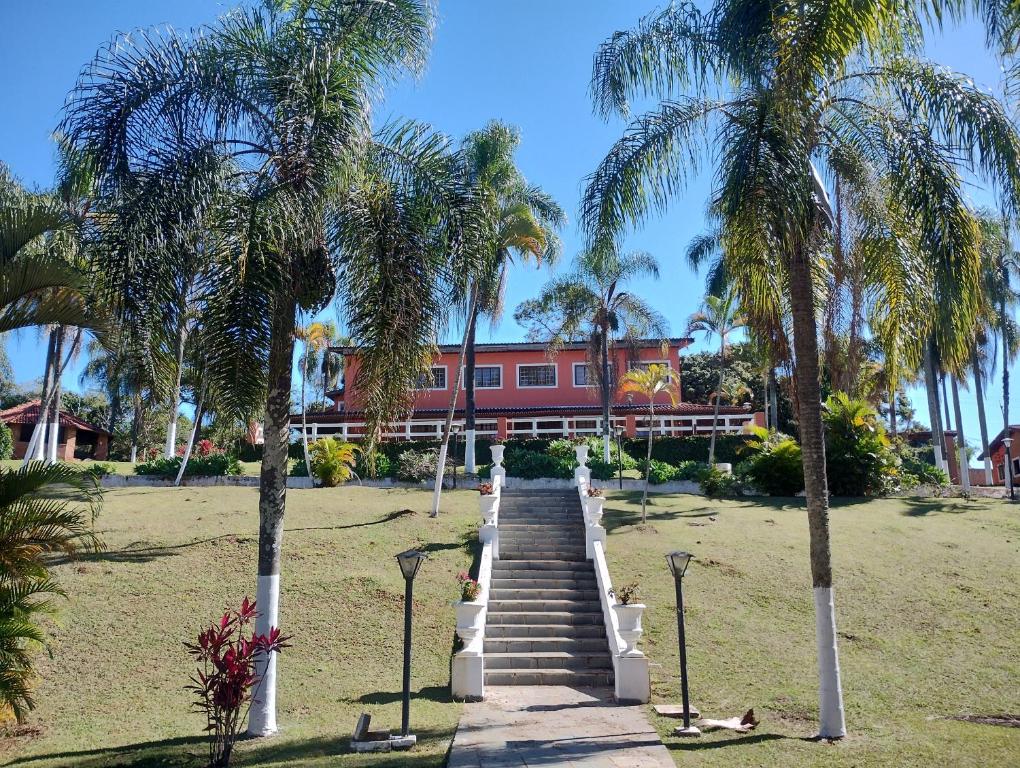 una scala che conduce a un edificio rosso con palme di Pousada Solar das Palmeiras a Joanópolis