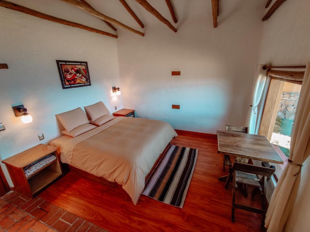 a bedroom with a large bed and a table at Ecolodge K'arasirca in Comunidad Yumani